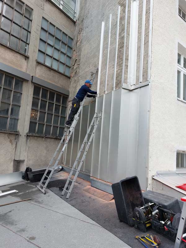 Meine professionelle Spenglerei Peter Schubert, München, installiert eine hochwertige Metallverblendung an der maroden Mauer, um dem Gebäude einen modernen und ansprechenden Look zu verleihen.